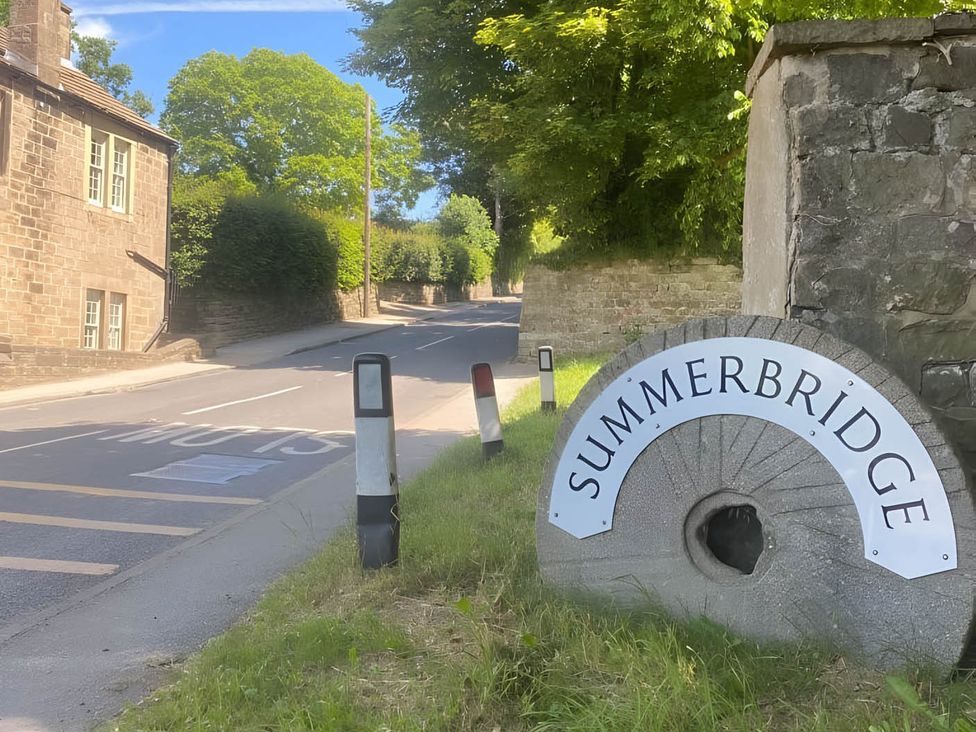 A road with a sign for Summerbridge and a stone structure at 2-Bed Flat in Summerbridge Harrogate, Pet Friendly