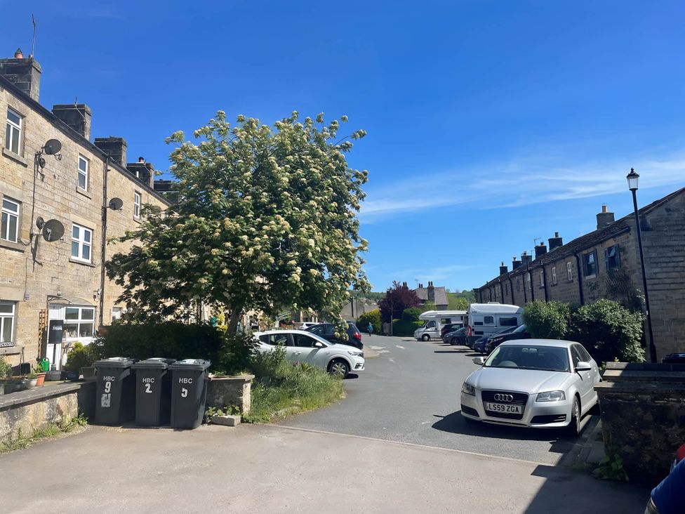 A parking area with cars and bins near buildings at 2-Bed Flat in Summerbridge Harrogate