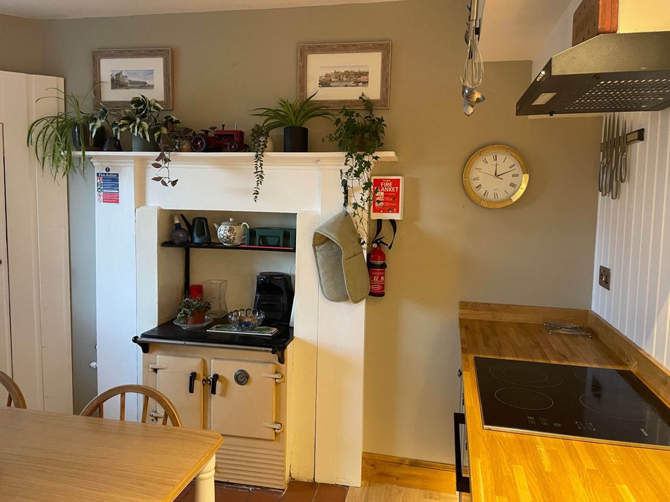 A kitchen with a stove and shelving at 1 Keepers Cottage, Skeabost Bridge, Isle Of Skye