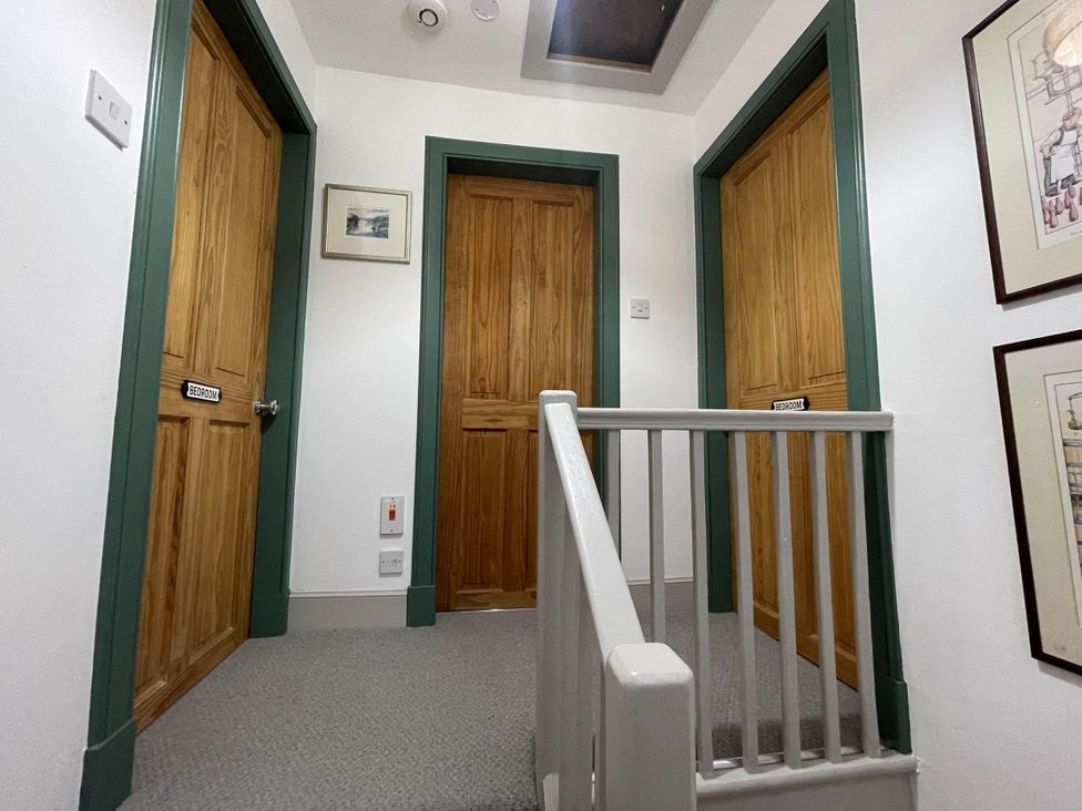 A hallway with doors leading to bedrooms and stairs at 1 Keepers Cottage, Skeabost Bridge, Isle Of Skye