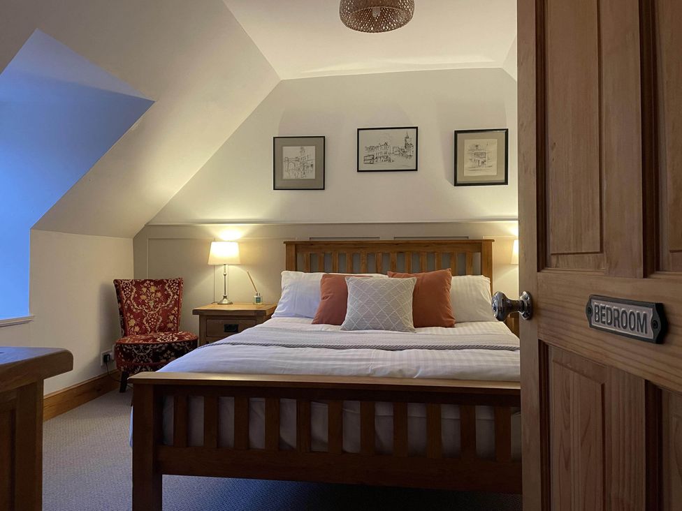 A bedroom with a bed and chair at 1 Keepers Cottage, Skeabost Bridge, Isle Of Skye