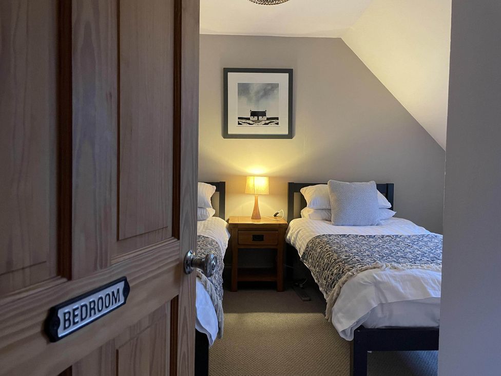 A bedroom with two beds and a nightstand at 1 Keepers Cottage, Skeabost Bridge, Isle Of Skye