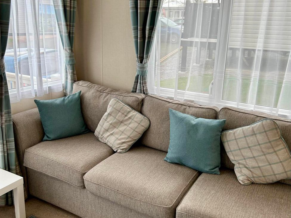A sofa with cushions and curtains at Static Caravan Hoburne Devon Bay