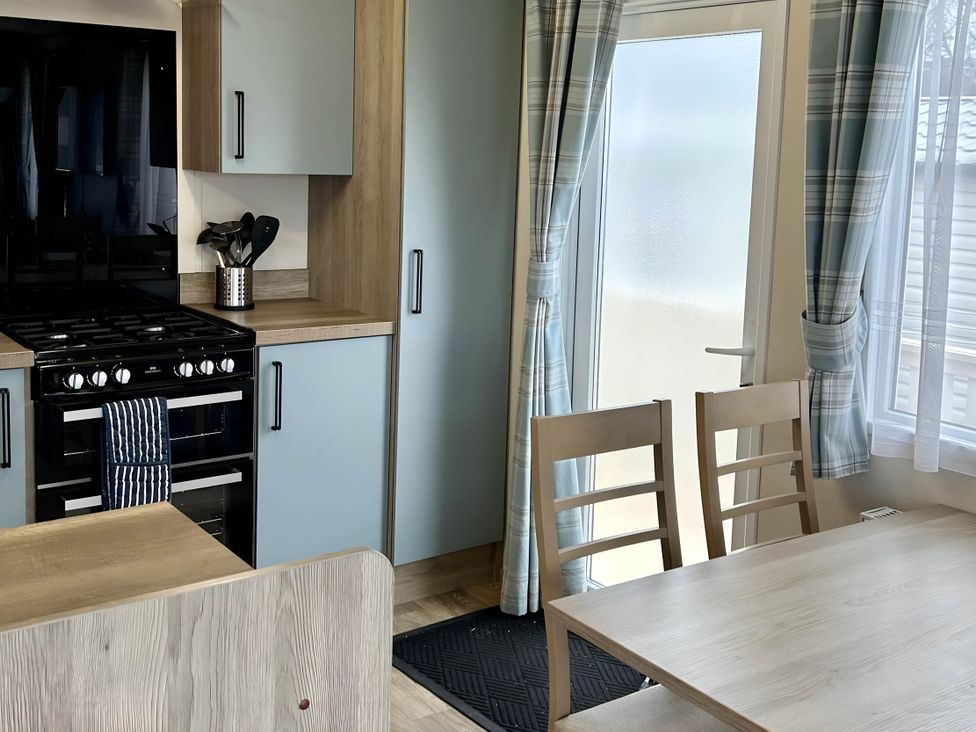 A kitchen with gas stove and dining table at Static Caravan Hoburne Devon Bay