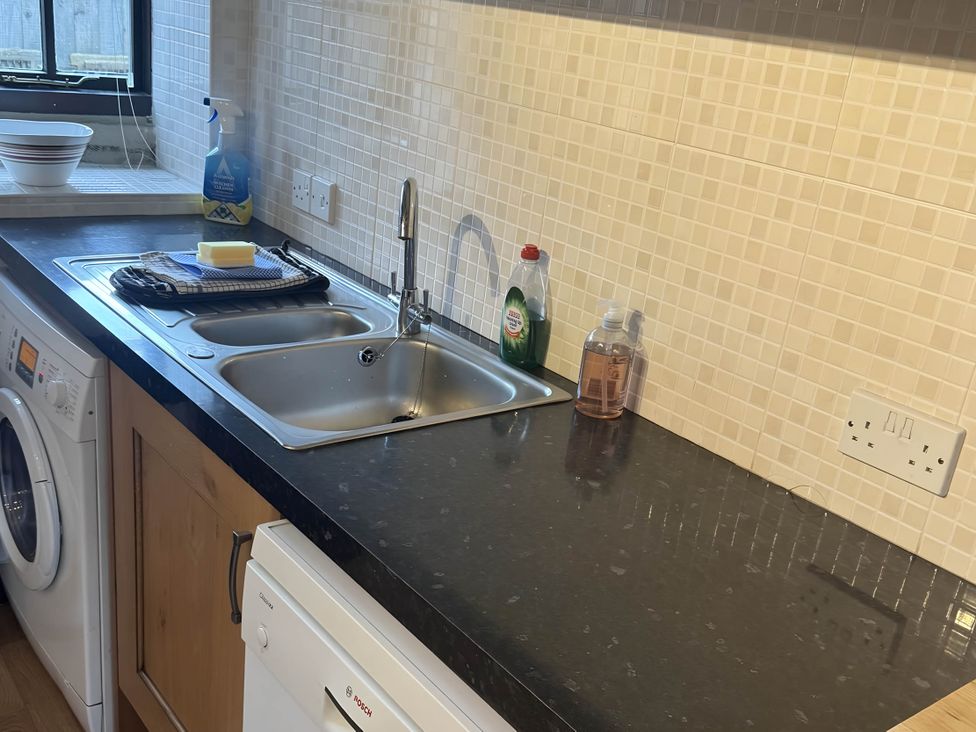 A kitchen with a sink and washing machine at Stunning cottage - 3 Bedrooms & 3 Bathrooms