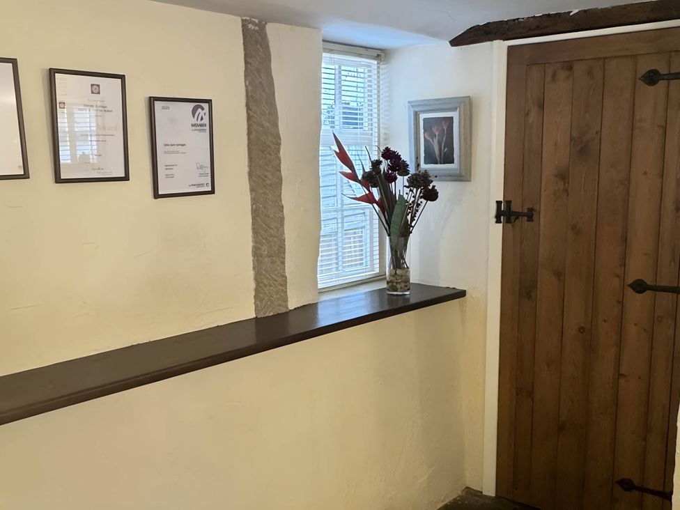 An entrance hall with a wooden door and certificates on the wall at Stunning cottage - 3 Bedrooms & 3 Bathrooms
