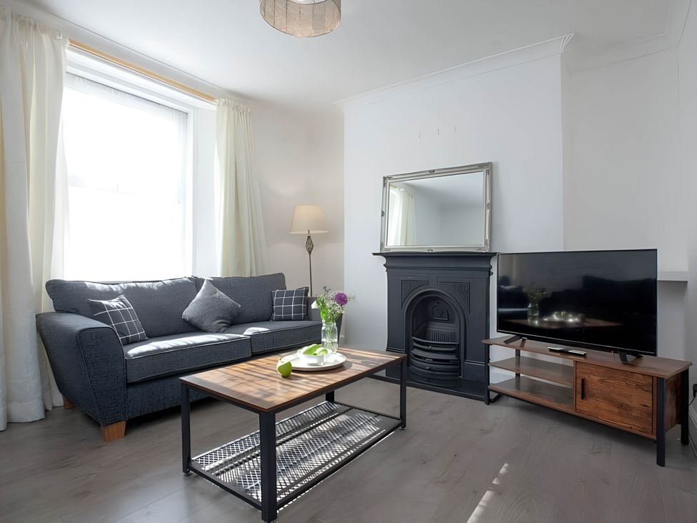 A living room with a sofa, coffee table, television, and lamp at Torquay - House - Sleeps 6 - Pet Friendly