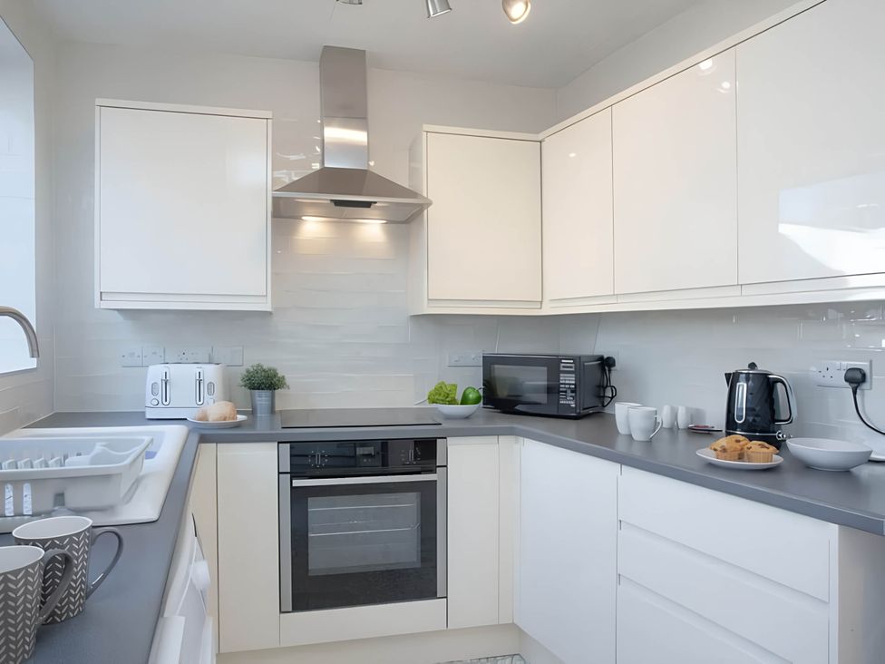 A kitchen with a stove, microwave, and countertop items at Torquay - House - Sleeps 6 - Pet Friendly