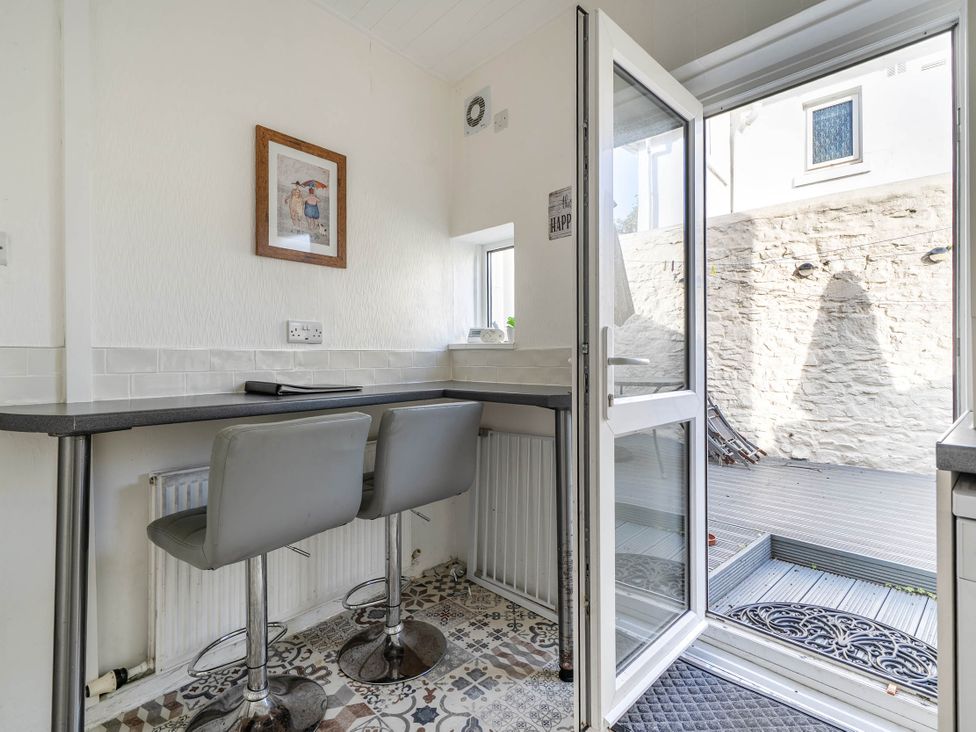 A kitchen with a table and bar stools at Torquay - House - Sleeps 6 - Pet Friendly, Torquay