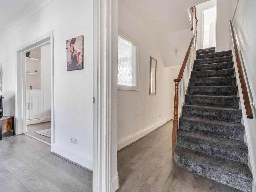 A hallway with a staircase and wall art at Torquay - House - Sleeps 6 - Pet Friendly, Torquay