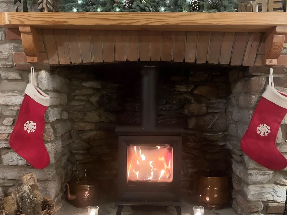 A fireplace with stockings and a wood stove at Quiet cottage on the rural edge of Brixham