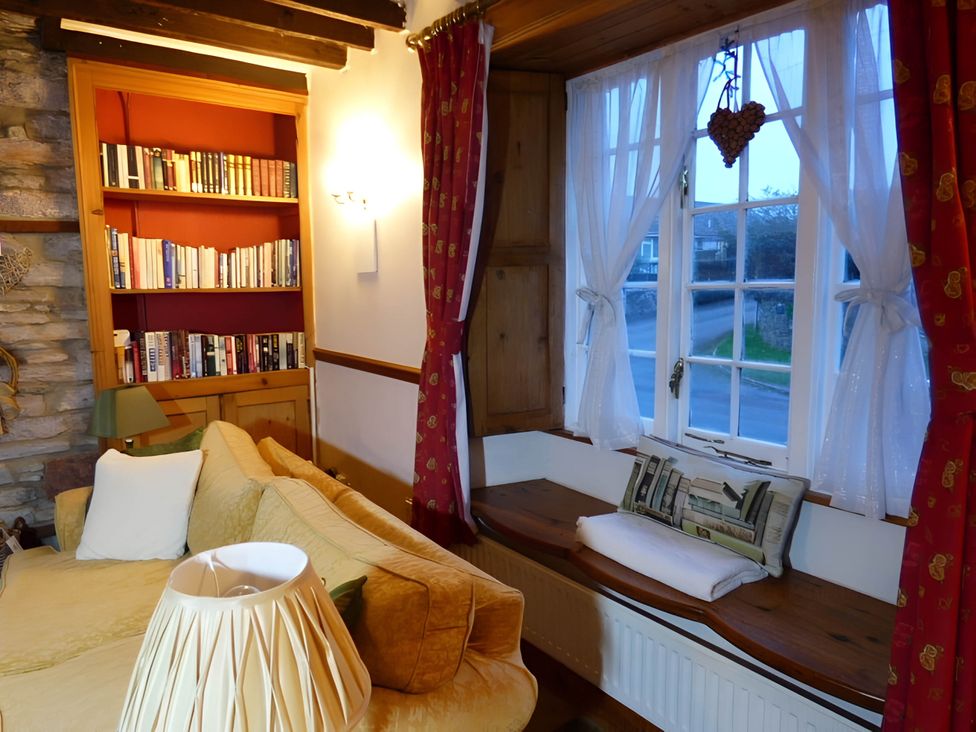 A living room with a sofa and books on a shelf at Quiet cottage on the rural edge of Brixham