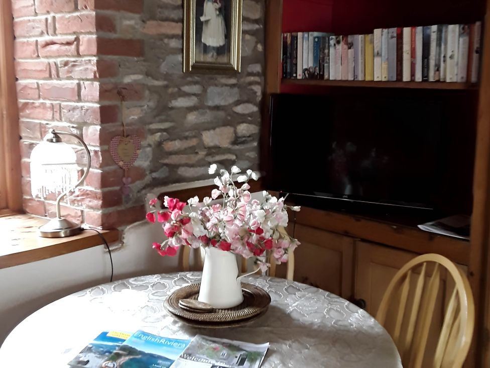 A dining room with a table, chairs, and a television at Quiet cottage on the rural edge of Brixham