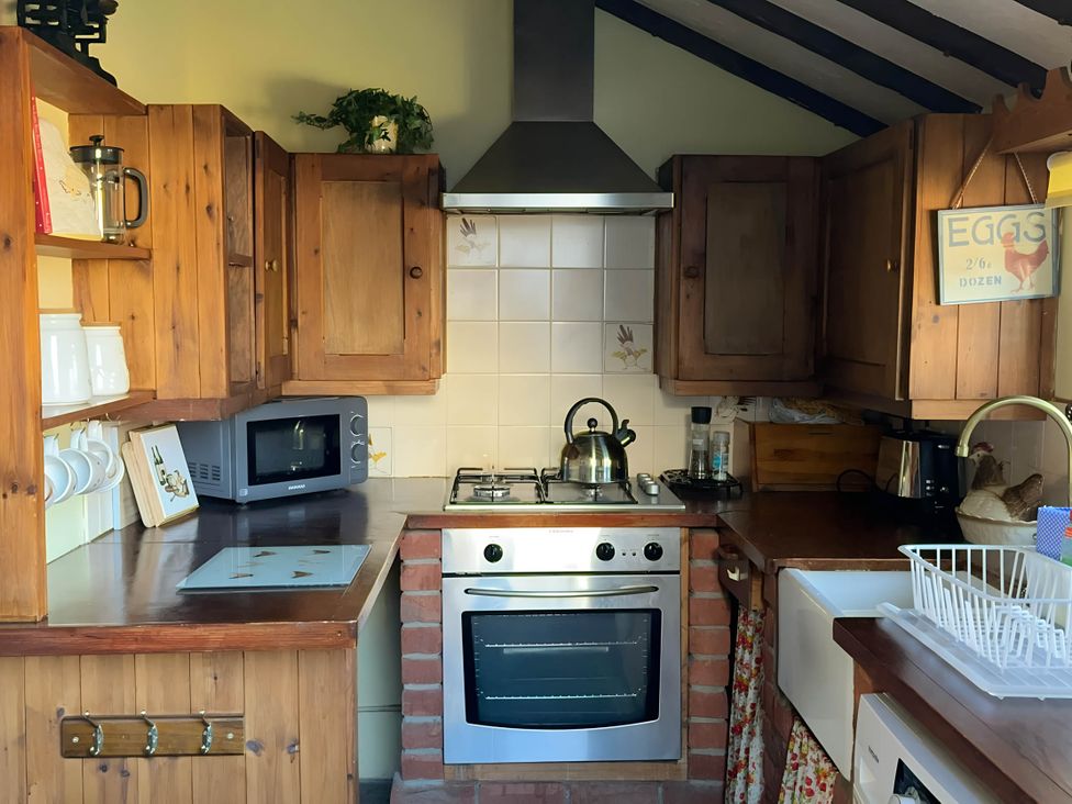 A kitchen with cabinets, stove, microwave, and sink at Quiet cottage on the rural edge of Brixham