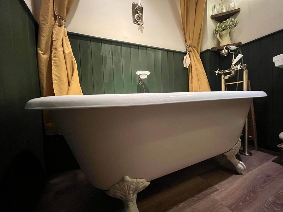 A bathroom with a bathtub and shower fixture at Quiet cottage on the rural edge of Brixham