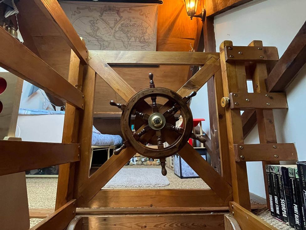 A ship's wheel and wooden stairs at Quiet cottage on the rural edge of Brixham