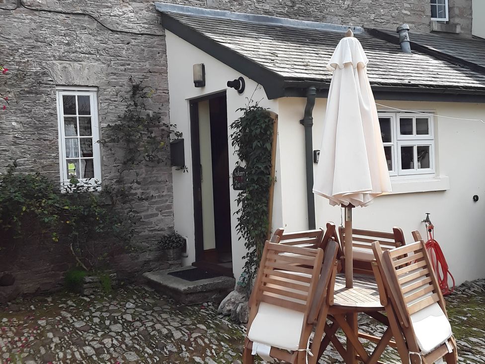 Outdoor area with table and chairs and an umbrella at Quiet cottage on the rural edge of Brixham