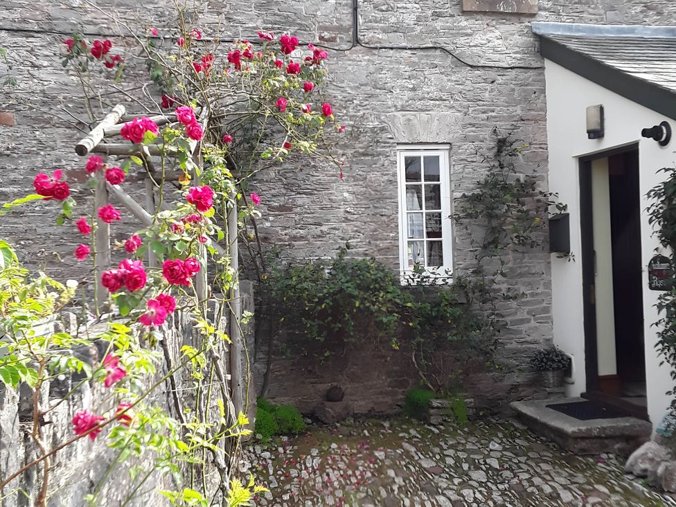 A garden with flowers and stone wall at Quiet cottage on the rural edge of Brixham