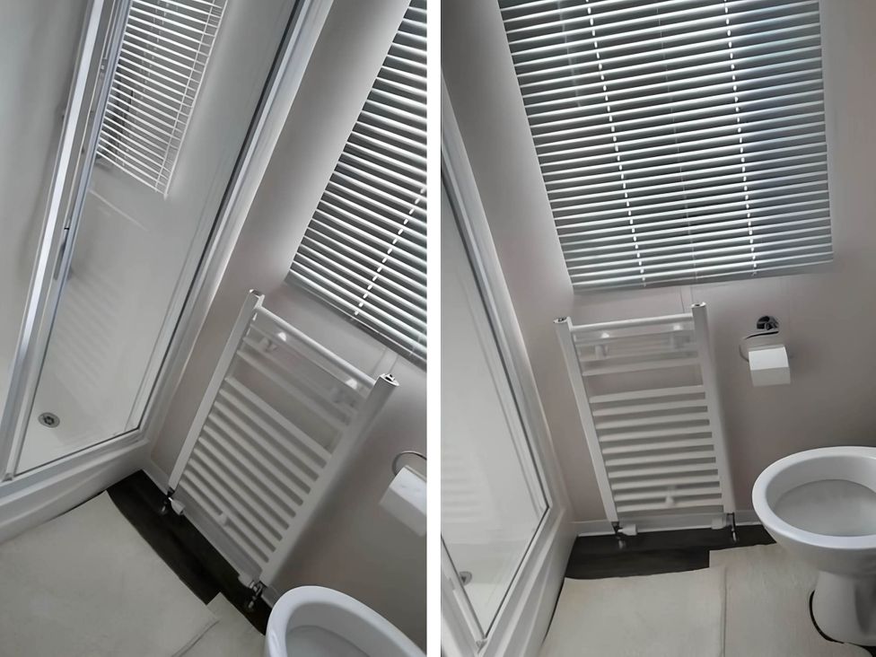 A bathroom with a shower enclosure, toilet, and radiator at Beverley bay 2-Bed Caravan, Sleeps 6, Pet Friendly