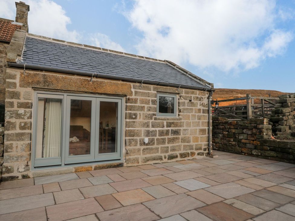 An outdoor view of a stone building with sliding doors and patio at Little Esklets in Whitby