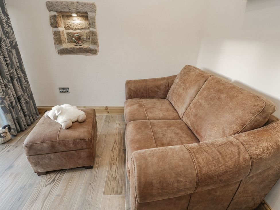 A living room with a sofa and an ottoman at Little Esklets in Whitby