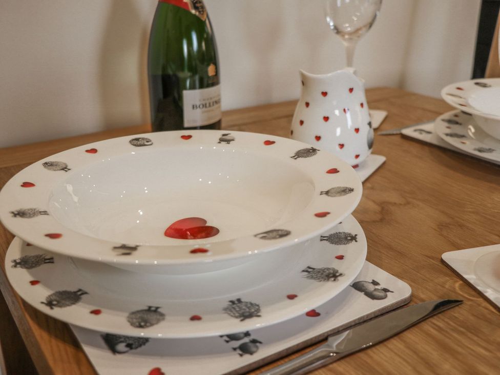 A dining table set with plates, a champagne bottle, and a sauce jug at Little Esklets in Whitby