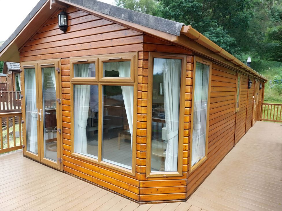 An exterior view of a log cabin with a deck and large windows at 2 Bed Lodge-Sleeps 4-stunning views -Pet Friendly, Troutbeck