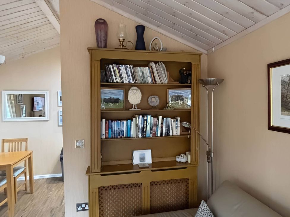 A living room with a bookshelf and dining table at 2 Bed Lodge-Sleeps 4-stunning views -Pet Friendly in Troutbeck