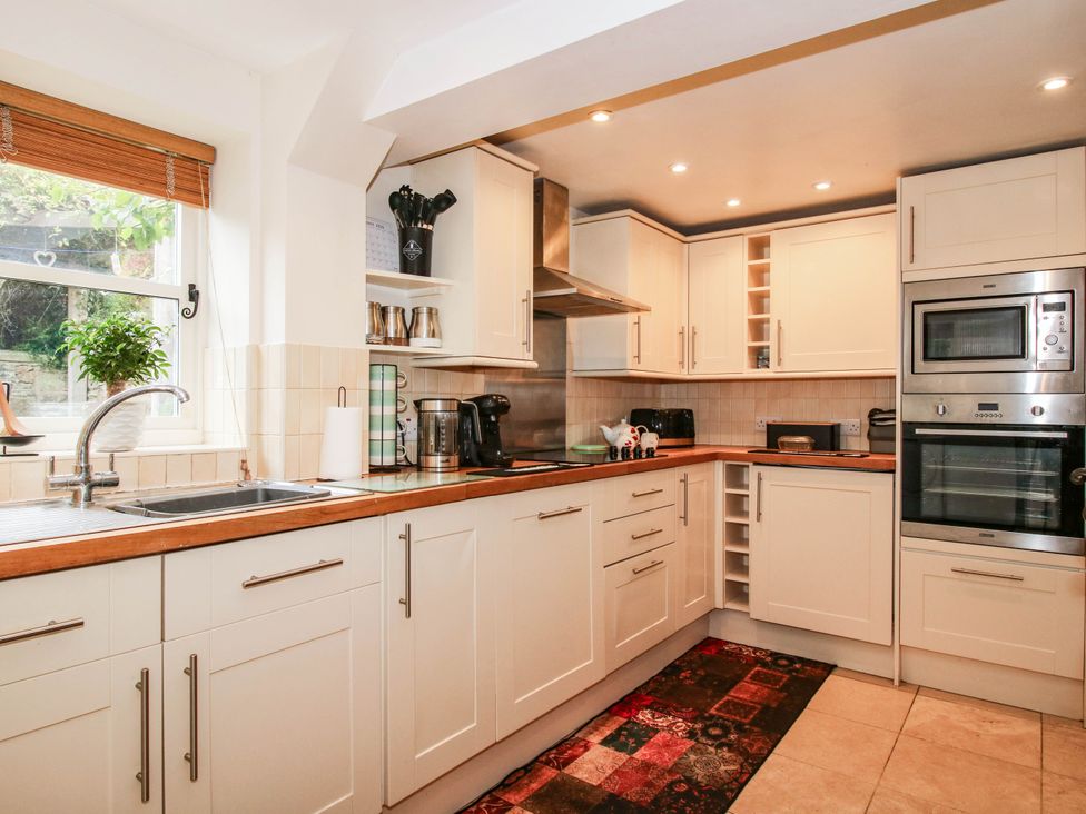 A kitchen with appliances and cabinets at Stone Cottage in Church Stretton