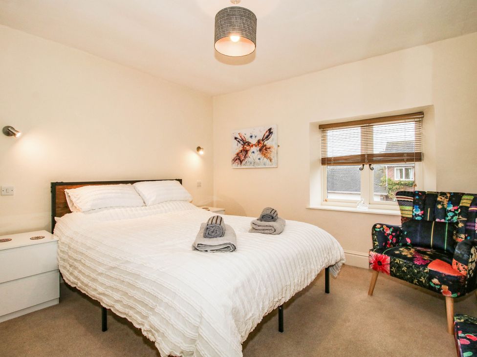 A bedroom with a bed and a chair at Stone Cottage in Church Stretton
