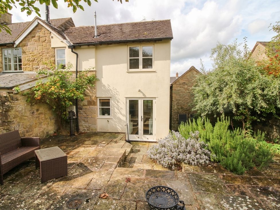 A garden with a patio area and a house at Stone Cottage Church Stretton