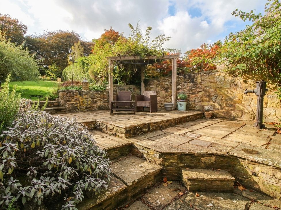 A garden with chairs and a stone patio at Stone Cottage in Church Stretton