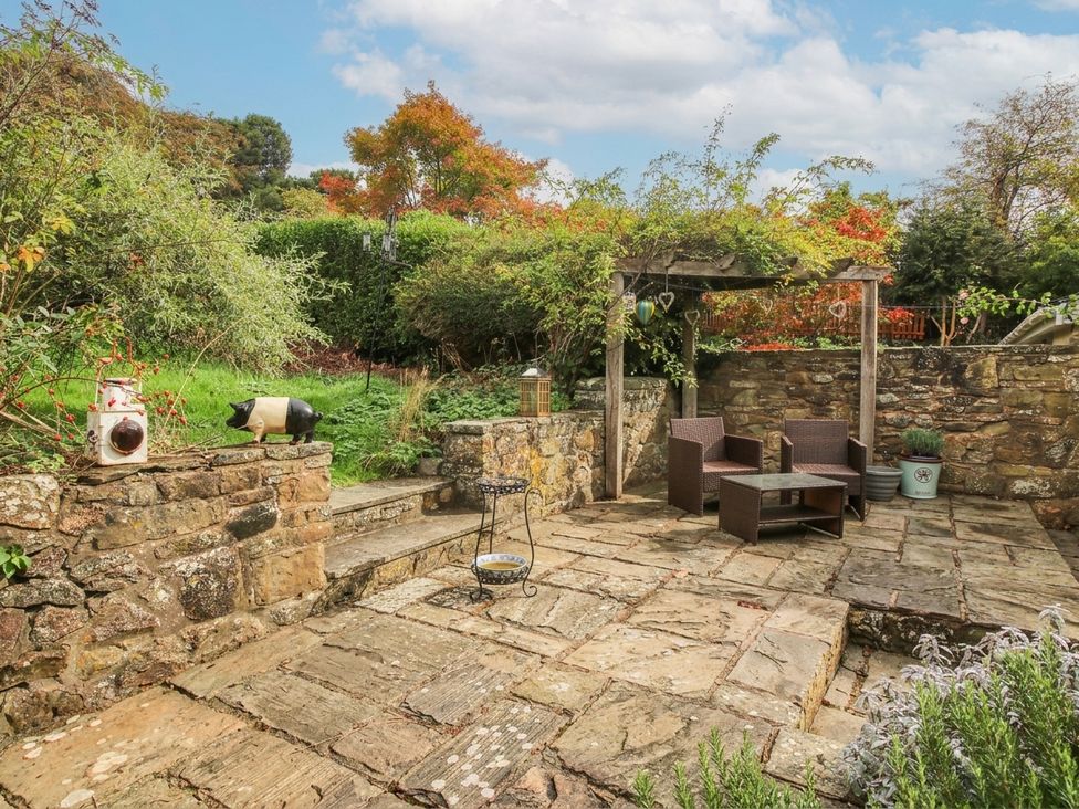 A garden with stone patio and seating at Stone Cottage in Church Stretton