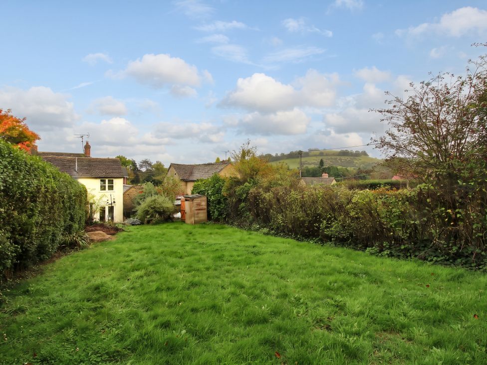 A garden with a house and grass at Stone Cottage in Church Stretton