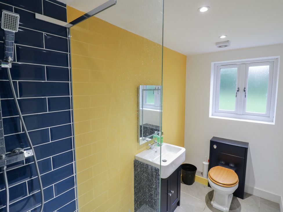 A bathroom with a shower, toilet, sink, and mirror at Ambercote in Priors Marston near Southam