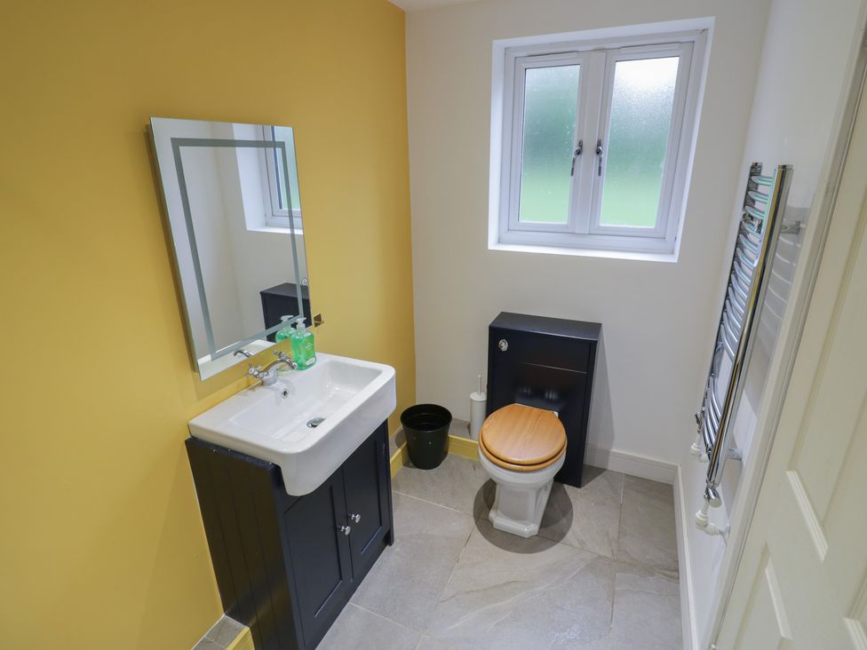 A bathroom with a sink, toilet, and mirror at Ambercote in Priors Marston near Southam