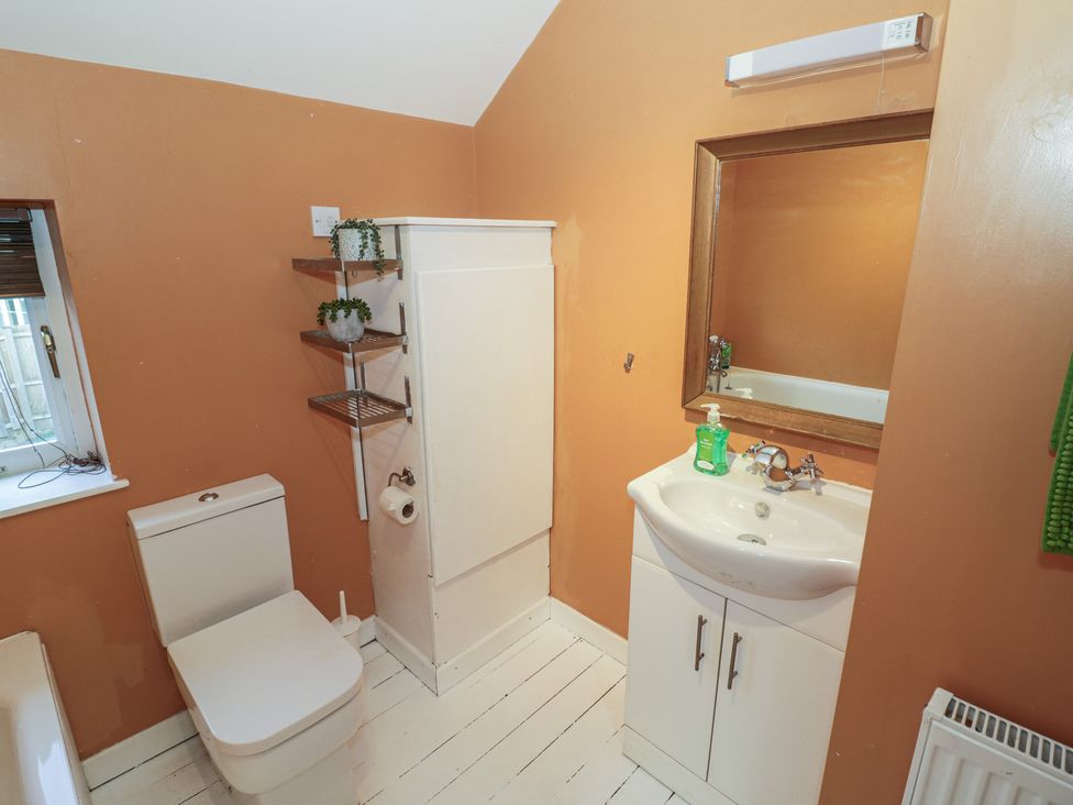 A bathroom containing a toilet, sink, and mirror at Ambercote in Priors Marston near Southam