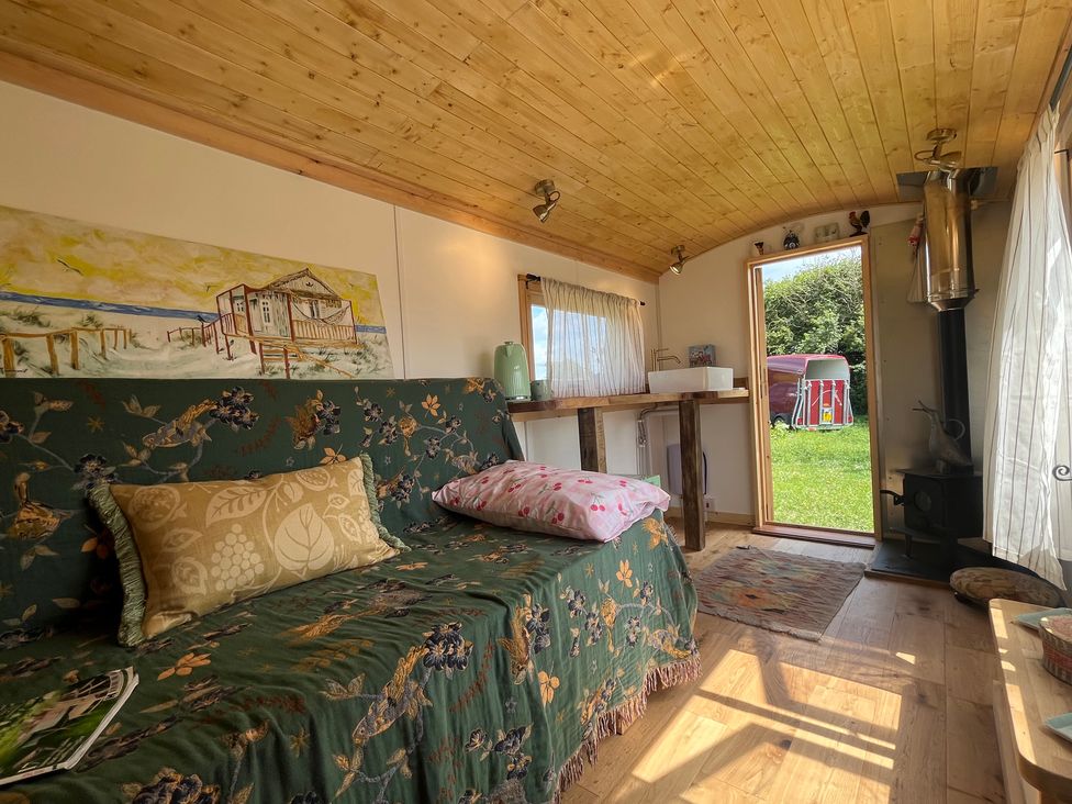 A living room with a sofa and table in the Shepherd Hut in Gloucester