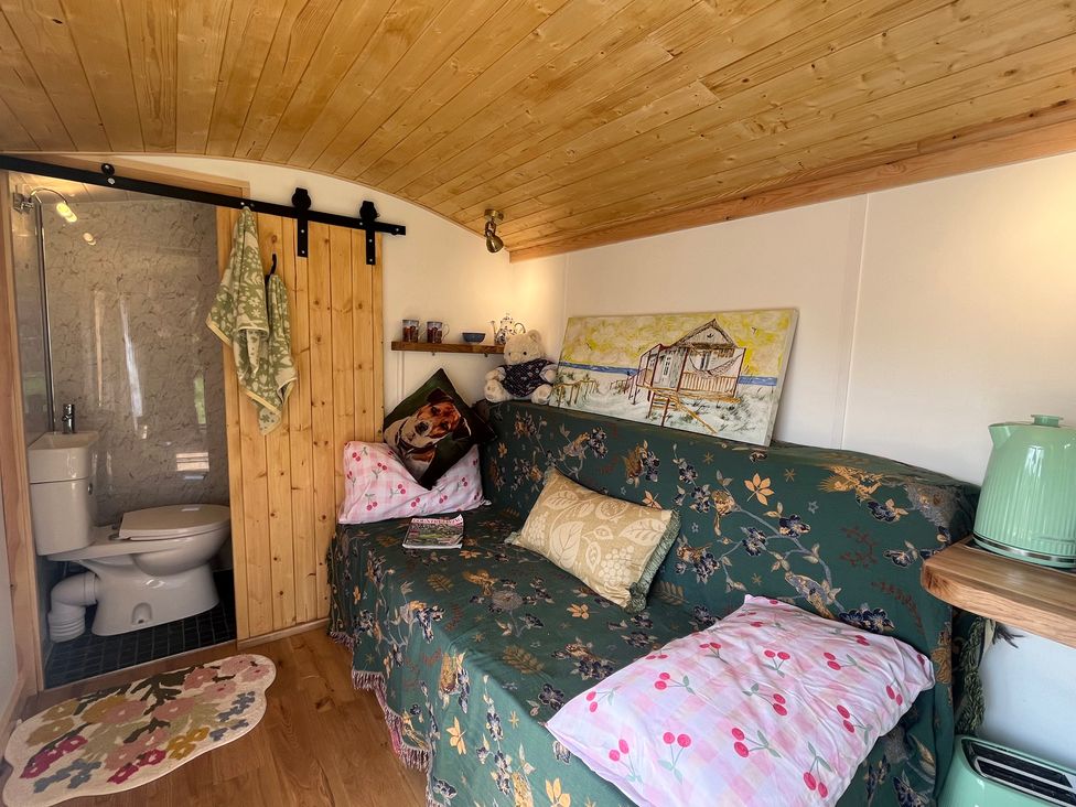 A living room with a sofa and a bathroom door at Shepherd Hut in Gloucester
