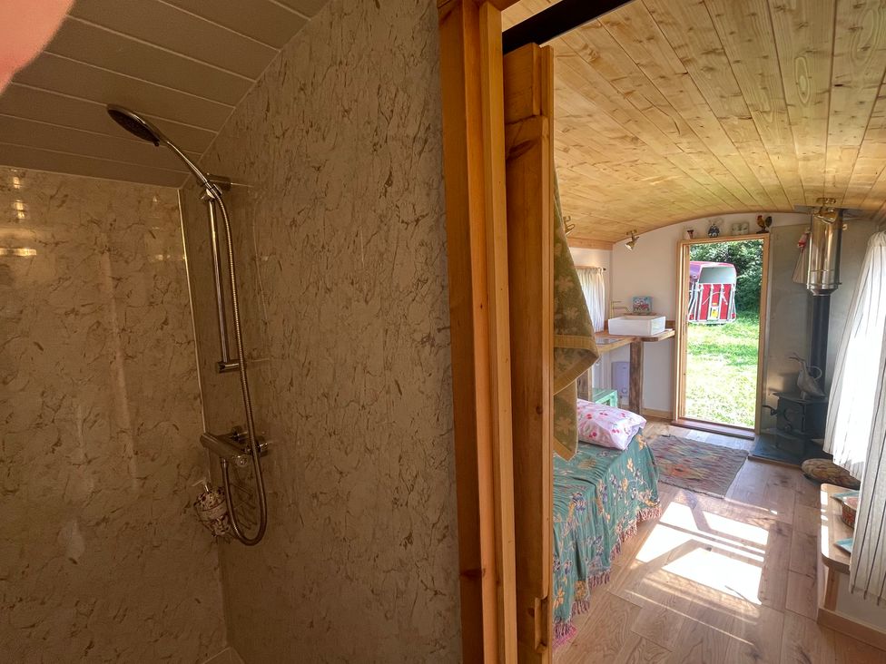 A bathroom with a shower and bedroom area at Shepherd Hut in Gloucester