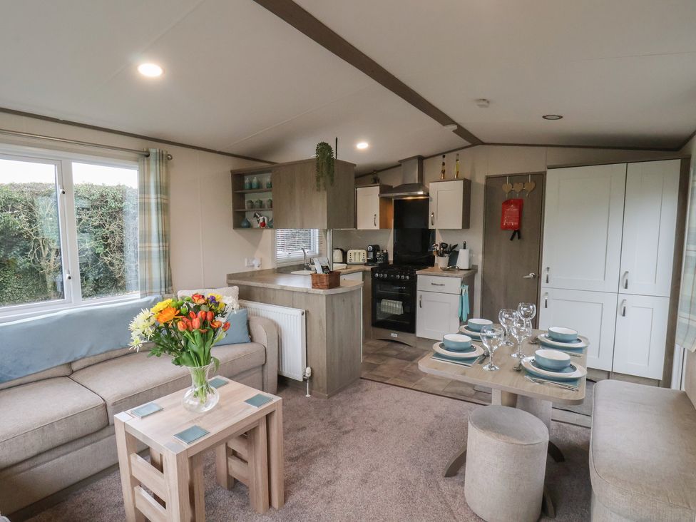 A living room with a sofa and kitchen area at Pepper Pot Lodge in Knaresborough