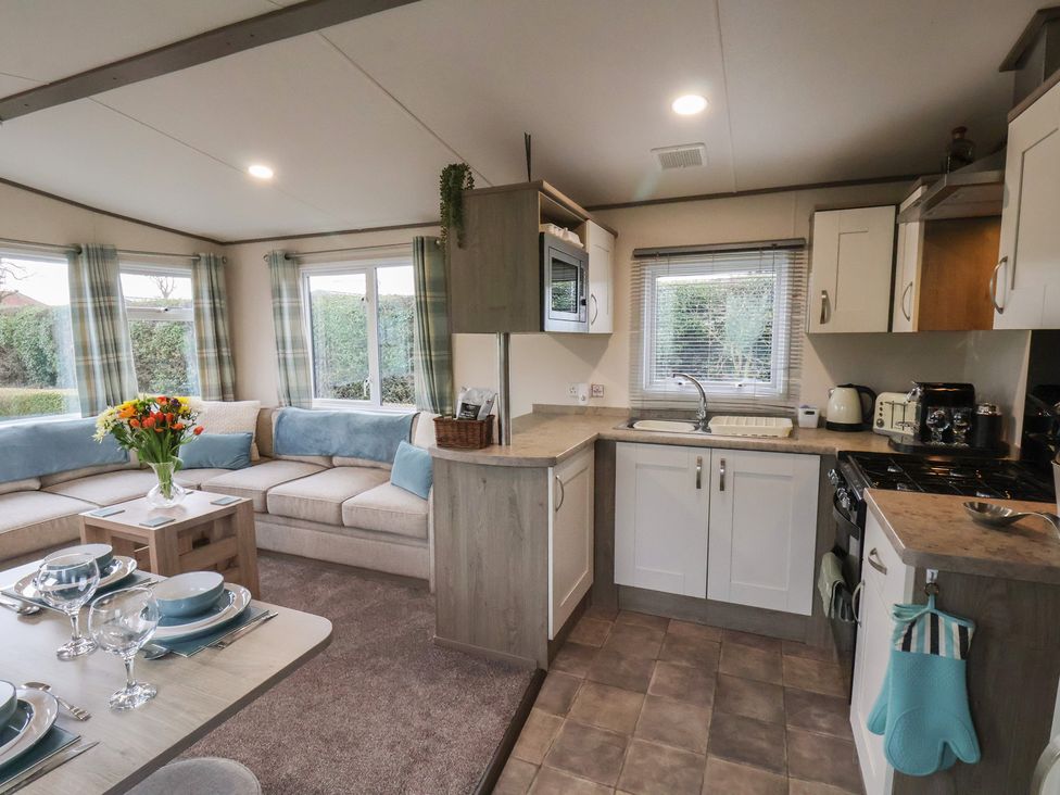 A kitchen and living area with sofa and dining table at Pepper Pot Lodge in Knaresborough