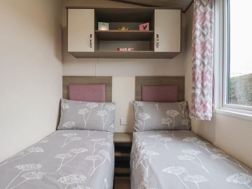 A bedroom with two beds and a wall cabinet at Pepper Pot Lodge in Knaresborough