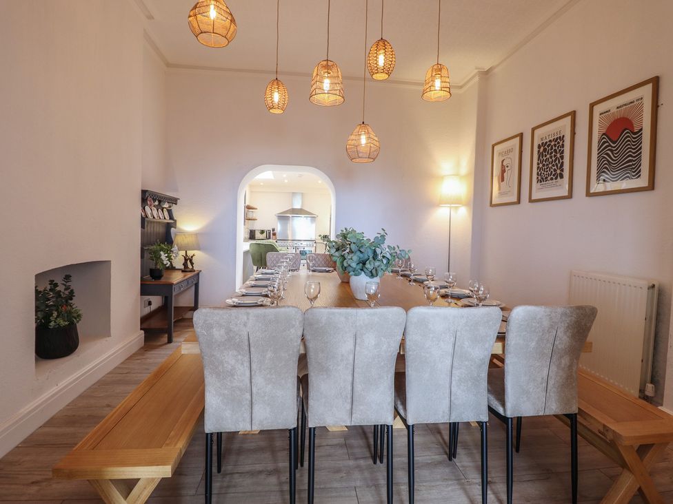 A dining room with a long table and chairs at Sea View, East Parade, Llandudno