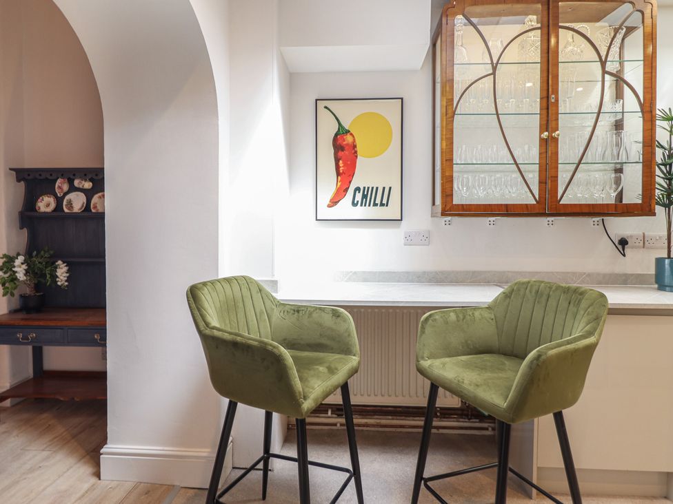 A kitchen with green chairs and wall art at Sea View, East Parade in Llandudno