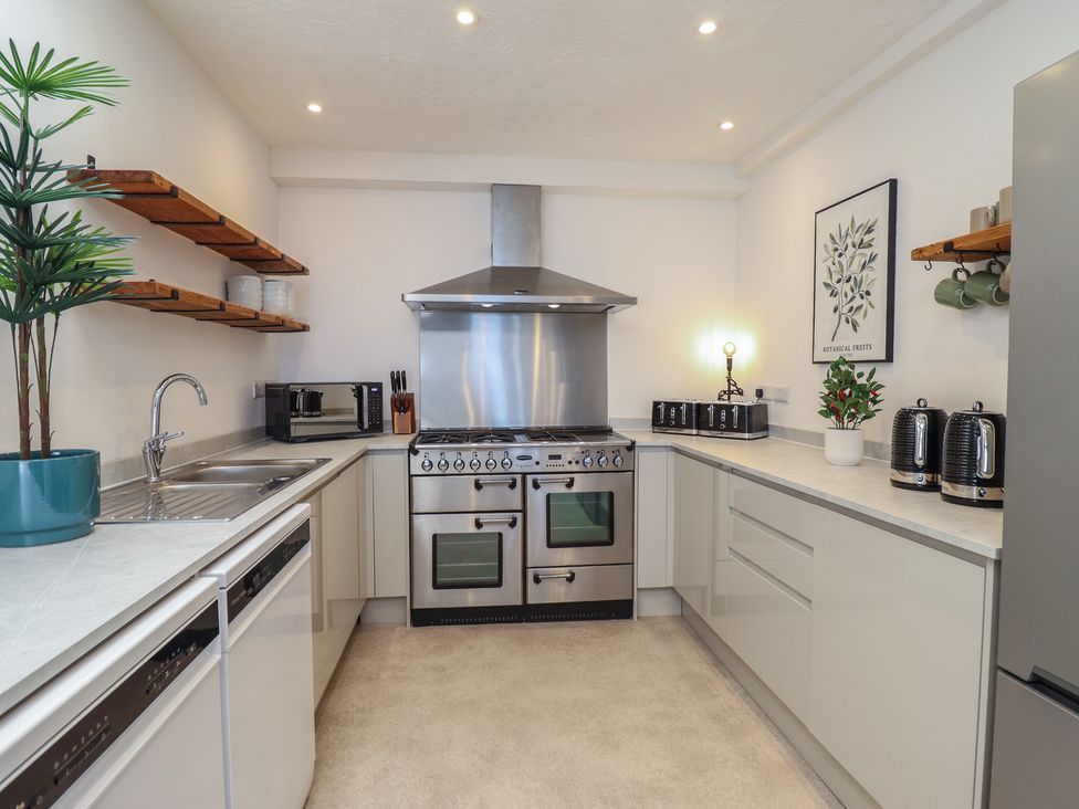 A kitchen with stove, sink, and microwave at Sea View, East Parade in Llandudno