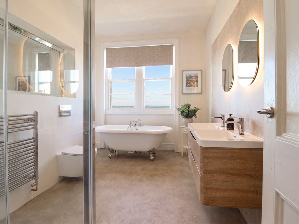 A bathroom with bathtub, sink, and towel radiator at Sea View, East Parade in Llandudno