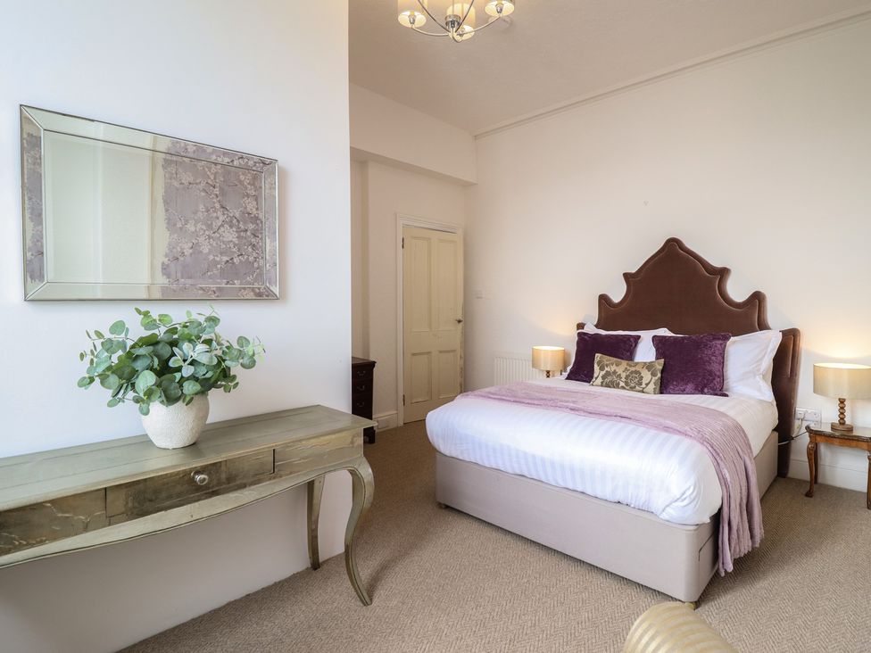 A bedroom with a bed and a mirror at Sea View, East Parade Llandudno