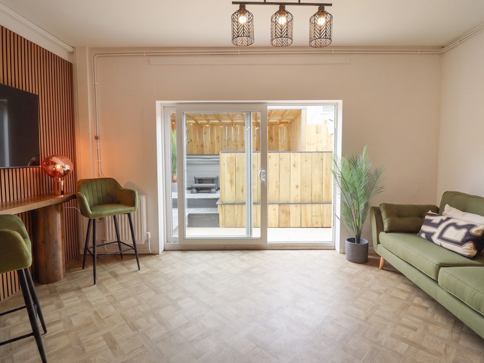 A living room with a sofa, table, chairs and a view of the outdoor area at Sea View, East Parade, Llandudno