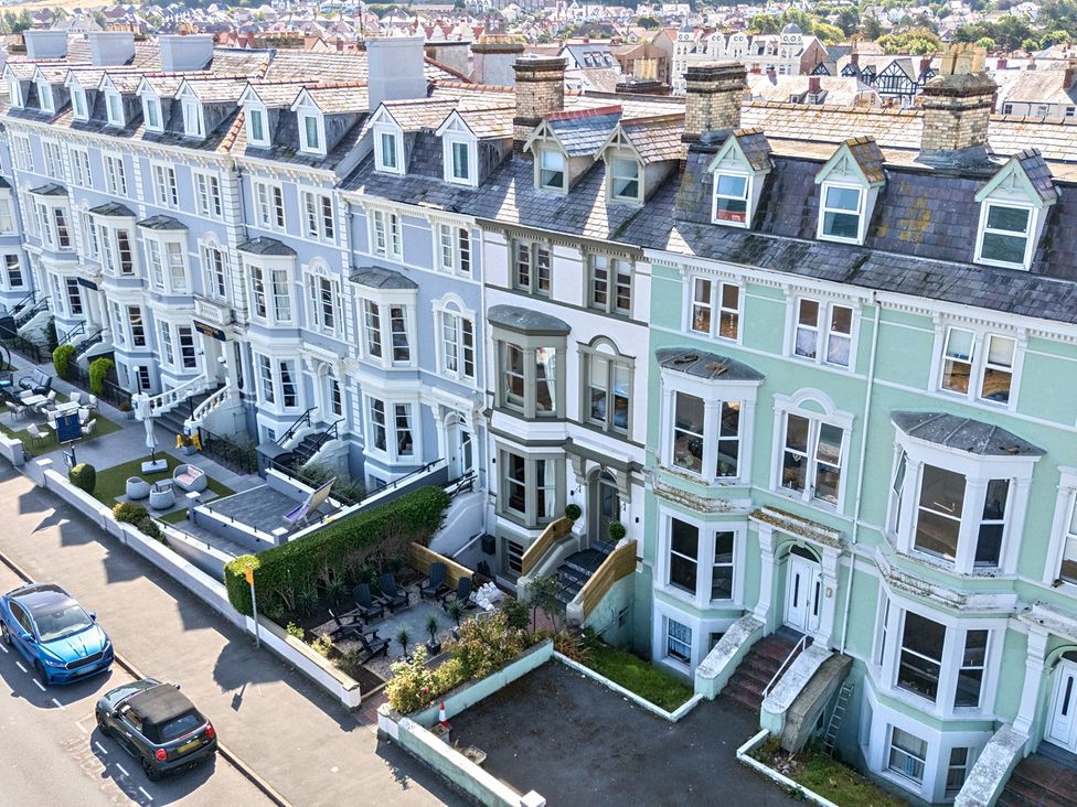A row of houses with gardens and vehicles at Sea View, East Parade in Llandudno